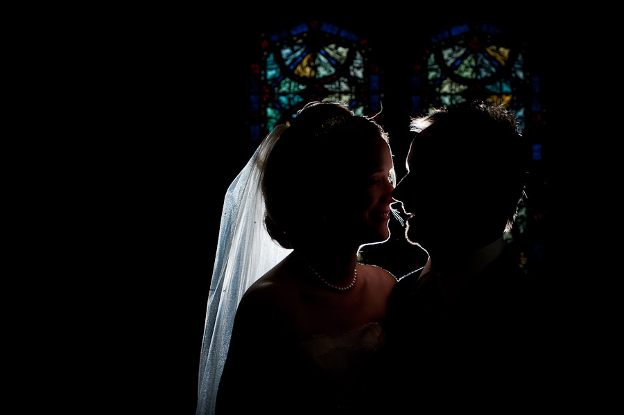 trinity-episcopal-terrys-catering-bloomington-wedding-23 strobist portrait of bride and groom in front of stained glass