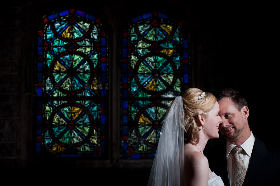 trinity-episcopal-terrys-catering-bloomington-wedding-08 strobist portrait of bride and groom with stained glass